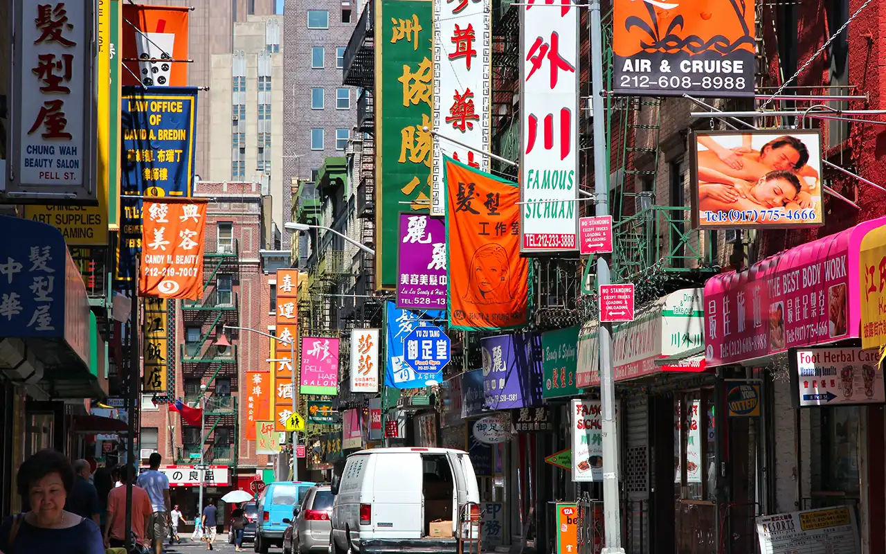 Vibrant street scene in Chinatown, New York, with busy shops, colorful signs, and pedestrians enjoying the lively atmosphere