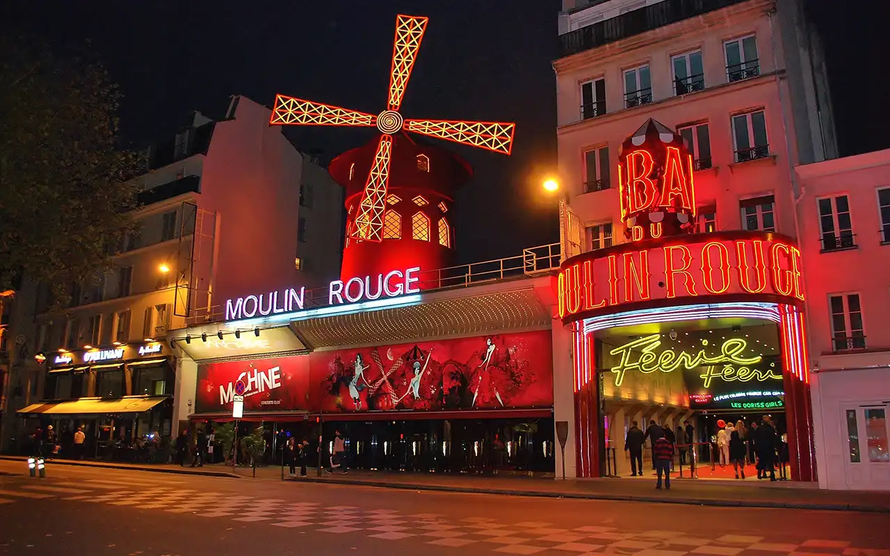 A vibrant image of Moulin Rouge, the iconic Parisian cabaret, with its red windmill and lively atmosphere
