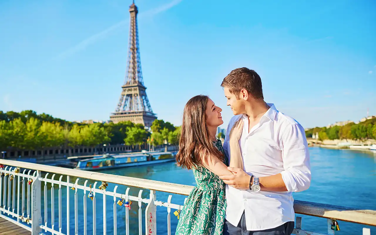 Romantic couple enjoying a leisurely walk along the Seine River, with the Eiffel Tower in the background