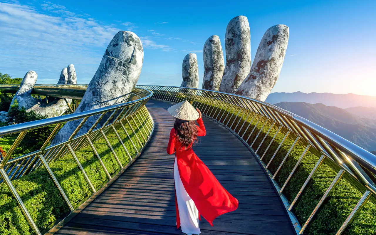 A woman in traditional Vietnamese attire walking on the Golden Bridge