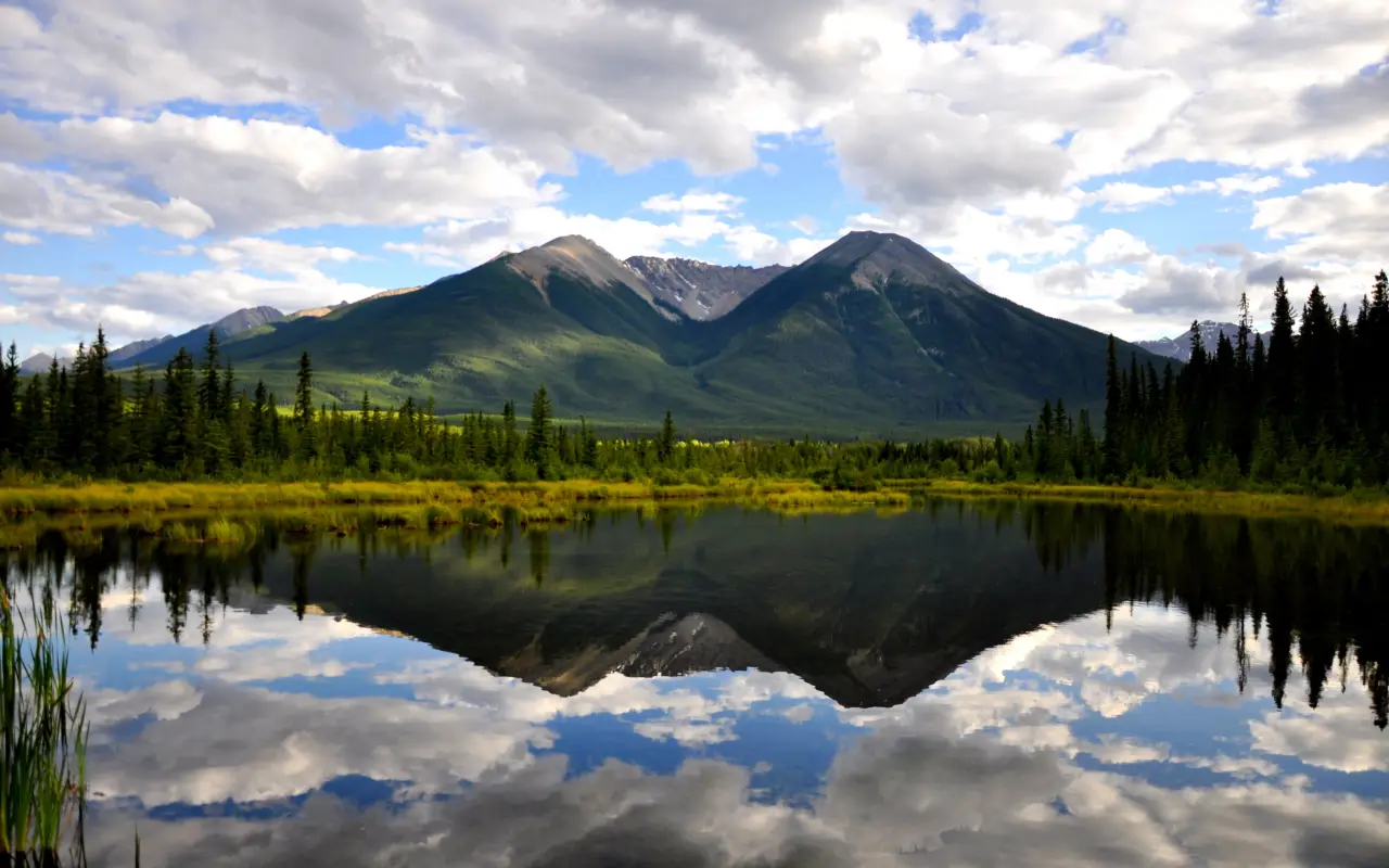 Serene landscape of mountains reflected in a calm lake with clouds above
