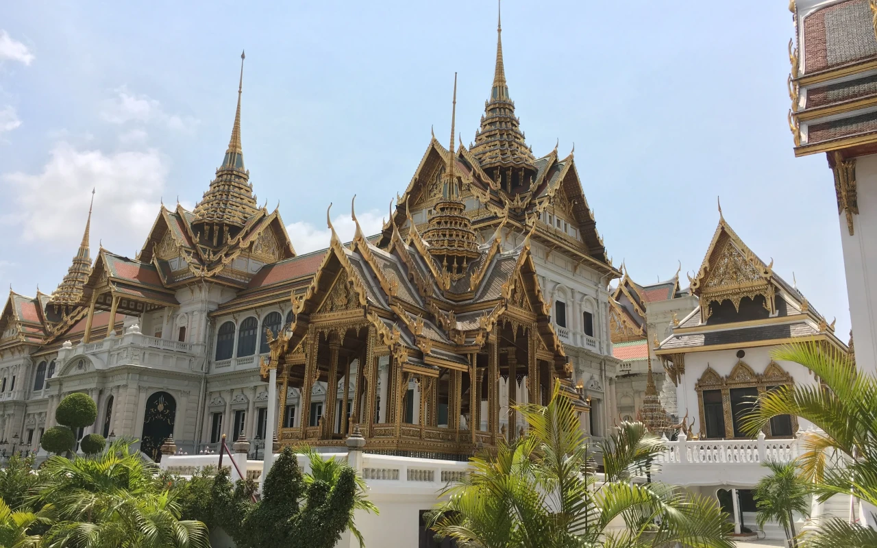 A majestic view of the stunning Grand Palace with intricately detailed architecture, surrounded by lush gardens and historical monuments.