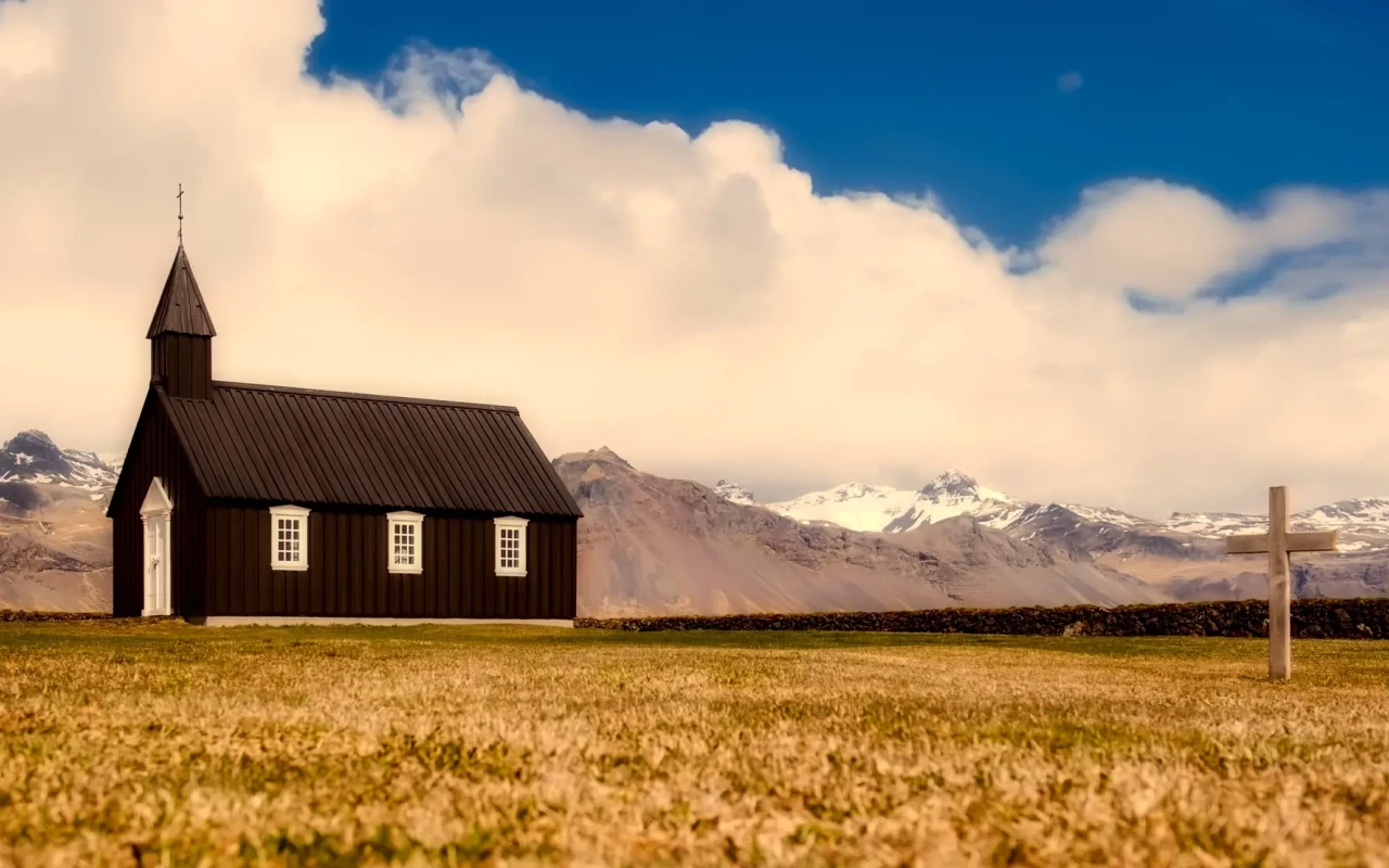 Scenic view of Iceland's stunning landscape with mountains, green plains, and a waterfall.