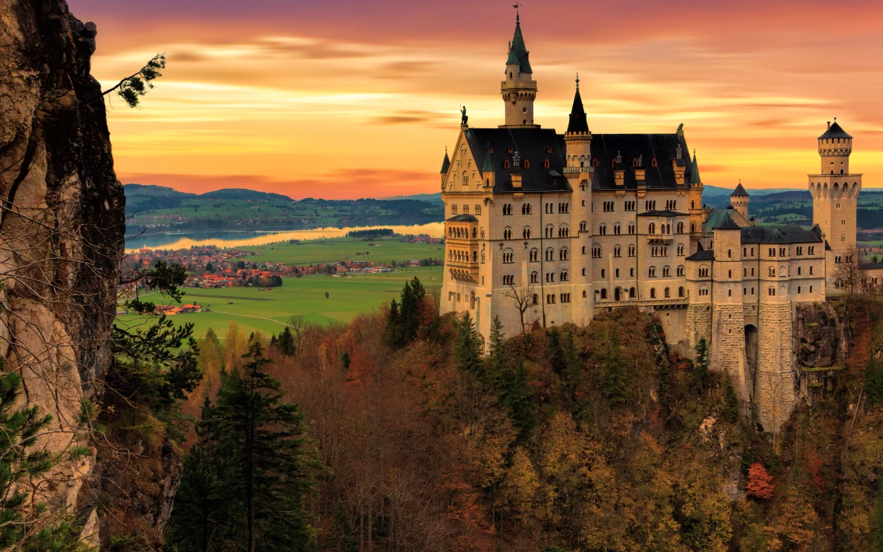 A majestic view of Neuschwanstein Castle surrounded by lush greenery and towering mountains.