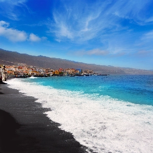 Candelaria black sand beach in Tenerife with its volcanic coastline and serene ocean waves.