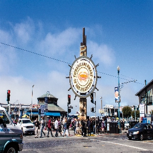 A bustling scene at Fishermans Wharf with boats docked, tourists exploring the area, and seafood vendors serving fresh catch.